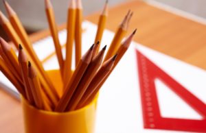 A cup of pencils on a desk with a ruler in the background