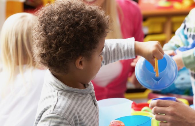 A young child playing with a tea pot