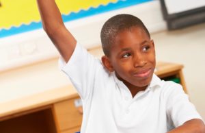 A young boy raising his hand