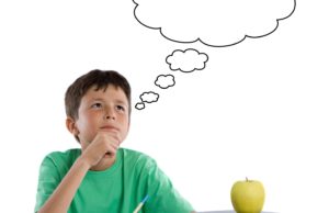 Young boy with a thought bubble and an apple on his desk