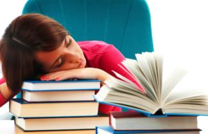 Boy looking helpless resting his head on a pile of books