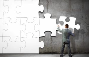 A man working on a large white puzzle on a concrete wall