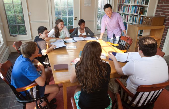 A teacher works with students around a table