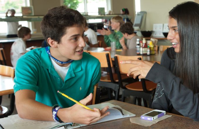 A student holding a pencil explains his thinking