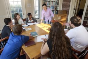 male teacher with a group of students around a table
