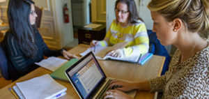 three women looking at laptops at a table