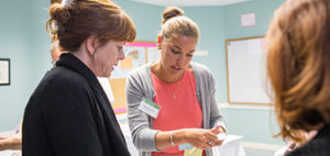 three adult woman talking in a classroom