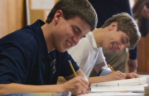 A boy takes notes at a desk