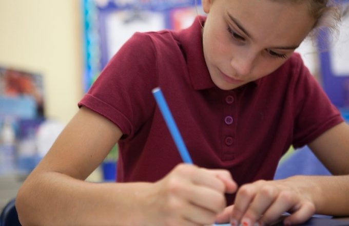 A young girl writes at a desk