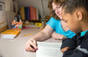 A teacher helps a young boy with reading