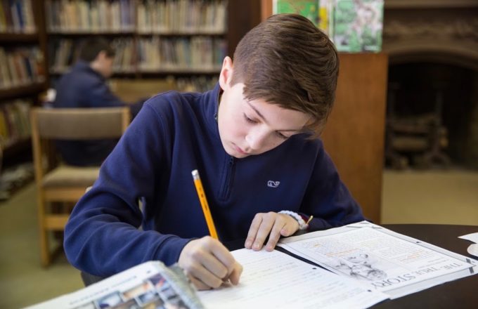 A young boy writes in a notebook