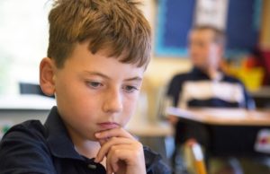 A young boy thinking in the classroom