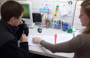 A teacher helps a young boy learn to read