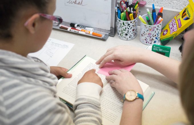 Student and teacher working collaboratively on reading a book