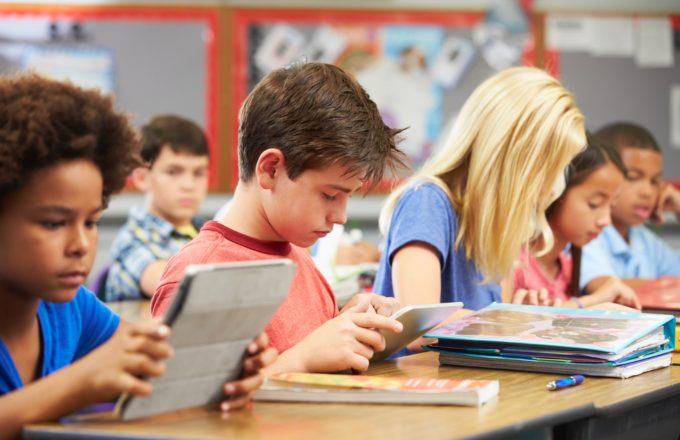 A young boy in a classroom using a e-reader