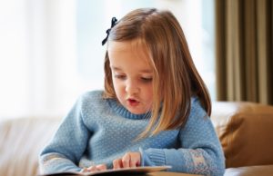 young girl reading a book on a couch