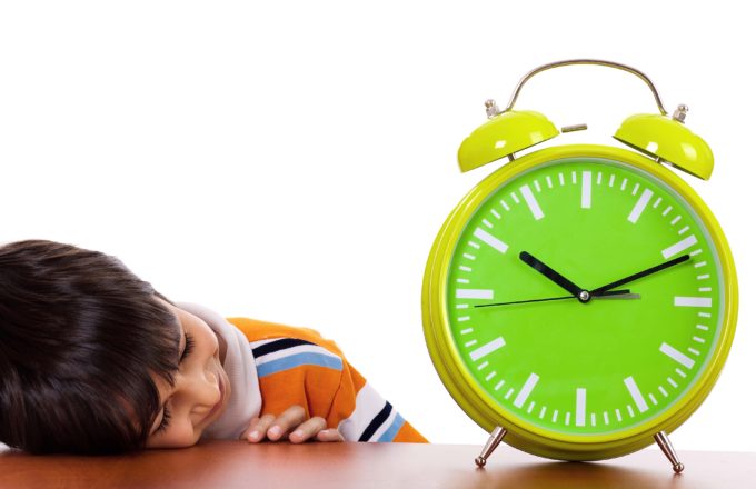 Boy tired of study and sleeping near the clock