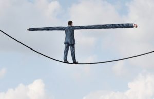 Adjust to risk with leadership solutions as a businessman with extremely stretched out arms for better balance walking on a tight rope to succeed at the road ahead as a business concept of adapting to challenges for strategy success.