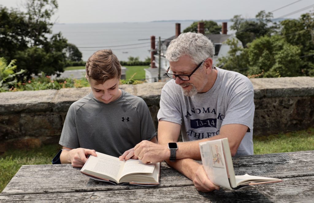 A teacher sitting next to a student to work one-on-one on reading comprehension.