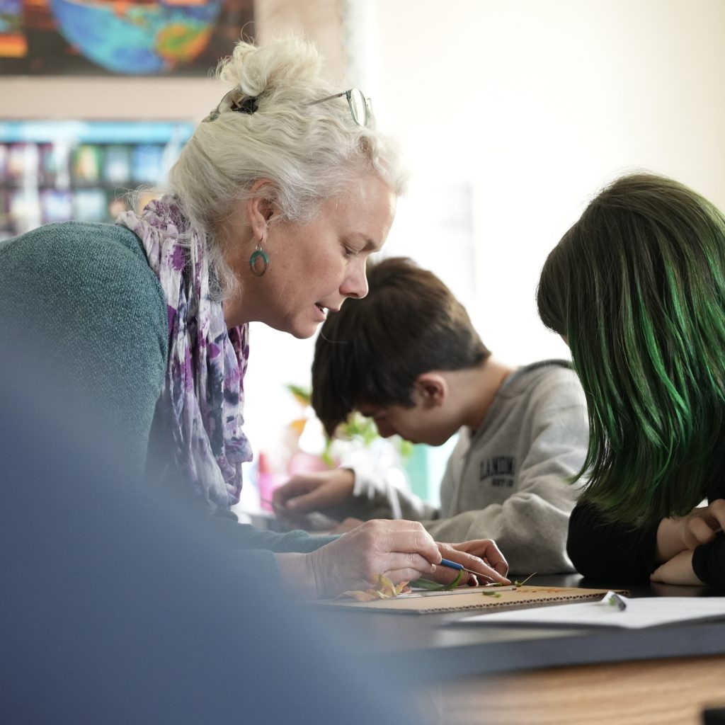 A teacher leans over to help a student with an assignment