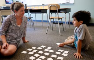 A teacher and student on the floor learn new vocabulary