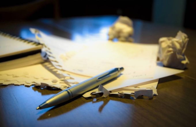 A silver pen on a piece of torn sheets of paper