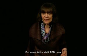 A picture of Carol Dweck-- woman with short dark hair and bangs, speaking on a stage