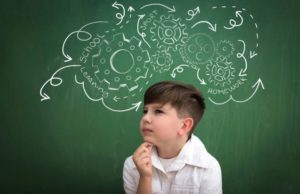 Young boy thinks and the process is shown on a chalk board behind him