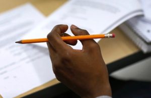 A hand holds a pencil over a notebook