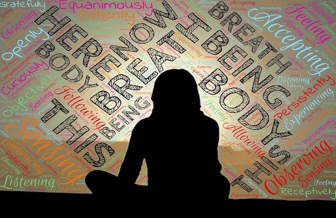 Silhouette of student meditating with mindfulness words surrounding