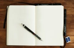 Notebook open, with pen lying across